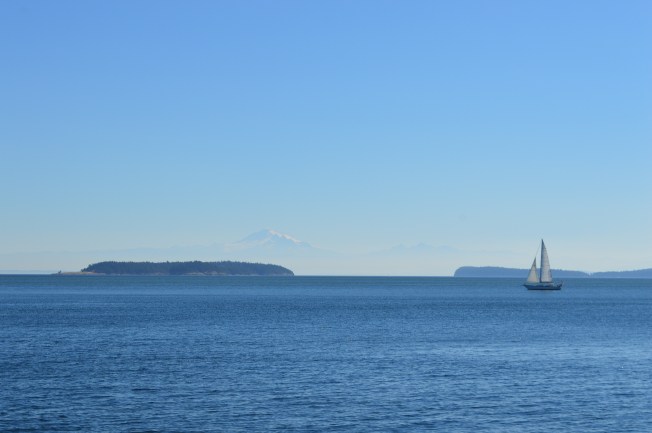 A sail boat on the ocean with a mountain in the background